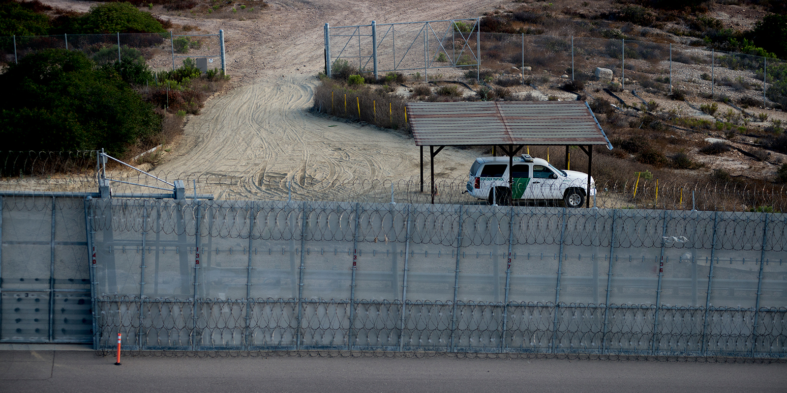 A Border Patrol agent vehicle sits between secondary fencing, which includes concertina wire at the top and bottom, and a basic chain-link fence, known as tertiary fencing. Photo was taken on Aug. 16, 2017. (Brandon Quester/inewsource)