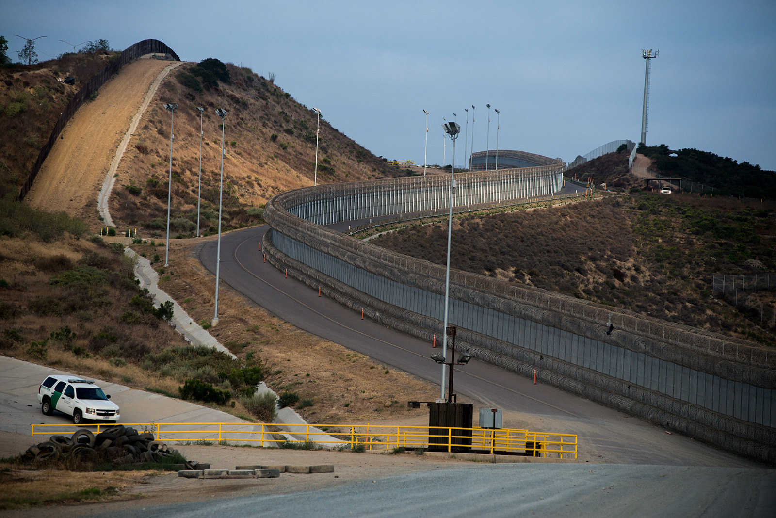 Two layers of fencing, one covered in concertina wire, follow a road near the San Ysidro Port of Entry in San Diego on Aug. 16, 2017.